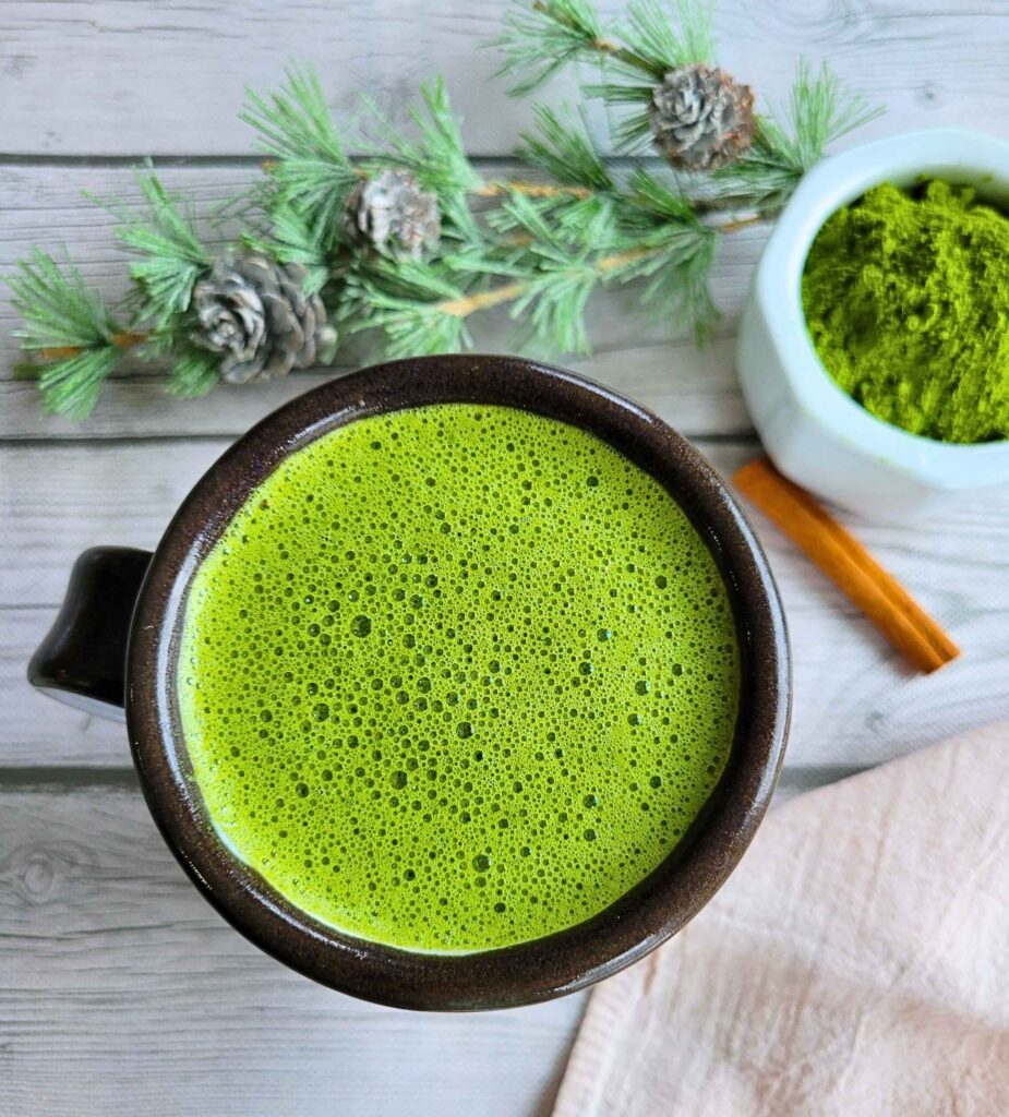 Anti-Inflammatory, Dairy-Free Matcha Latte in a mug next to fresh gut-healthy matcha powder.