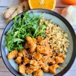 gut-healthy, ginger orange chicken with anti-inflammatory ingredients in a bowl over cauliflower rice and fresh arugula