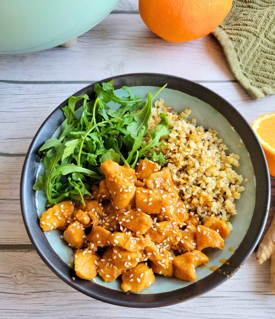 Anti-inflammatory ginger orange chicken in a bowl with cauliflower rice and fresh arugula