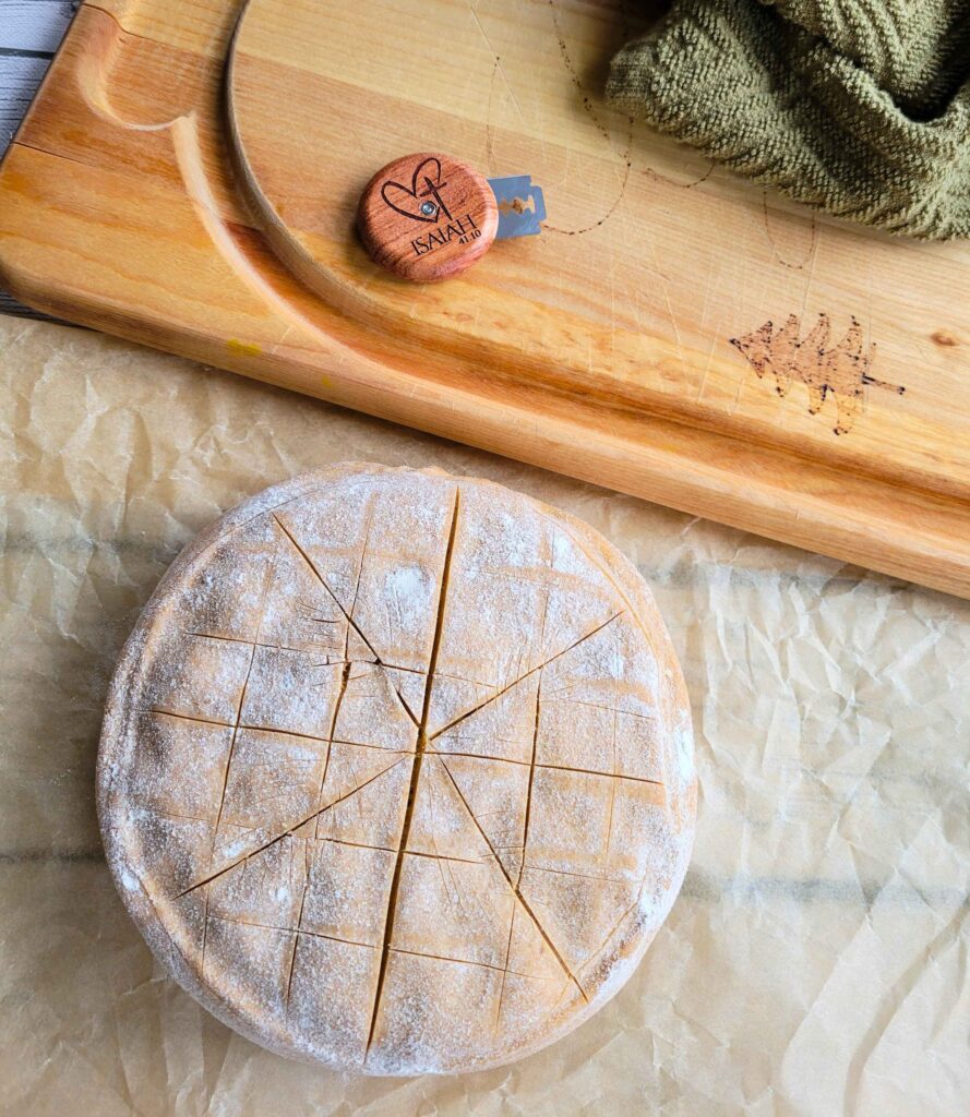 scoring a boule of whole grain einkorn sourdough to get it ready to bake
