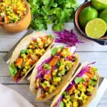 baked anti-inflammatory fish tacos on gut-healthy tortillas topped with fresh purple cabbage, cilantro, mango salsa, and lime